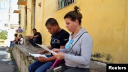 Migrantes cubanos chequean sus documentos mientras esperan para aplicar al asilo y el estatus de refugiado en México, Tapachula.