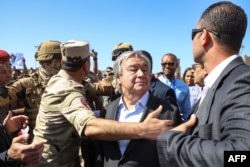 Los manifestantes levantan carteles en solidaridad con los palestinos en la Franja de Gaza mientras oficiales y guardaespaldas del ejército egipcio escoltan al Secretario General de las Naciones Unidas, Antonio Guterres (Foto de Kerolos SALAH / AFP)