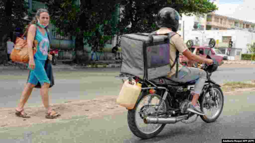 Un hombre en una motocicleta recorre las calles con un bidón de gasolina de reserva colgado de su moto en La Habana el 14 de abril de 2023. (Foto de ADALBERTO ROQUE / AFP)