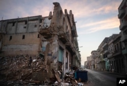 Edificios ruinosos y derrumbados bordean la calle San Lázaro, donde un hombre, a la izquierda, recoge ladrillos en el centro de La Habana (10 de octubre de 2023). (AP/Ramón Espinosa).