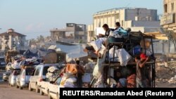 Palestinos desplazados, que huyeron de Rafah después de que el ejército israelí comenzara a evacuar a civiles, antes de una amenaza de asalto, viajan en un vehículo, en Khan Younis, el 6 de mayo de 2024. (REUTERS/Ramadan Abed)