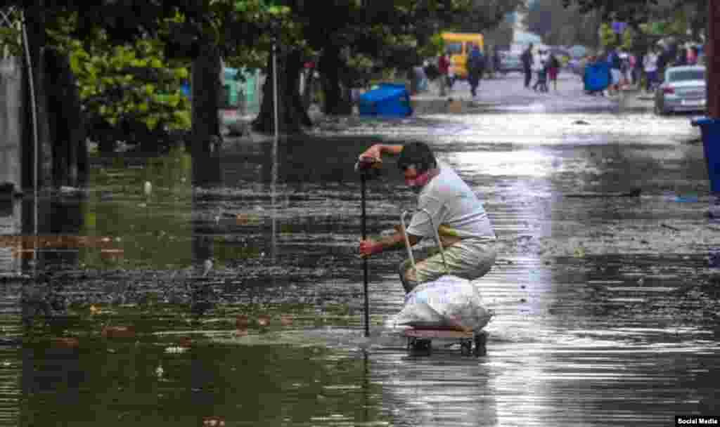 Un vecino destupe una alcantarilla en una calle inundada de El Vedado. (Facebook Canal Caribe)