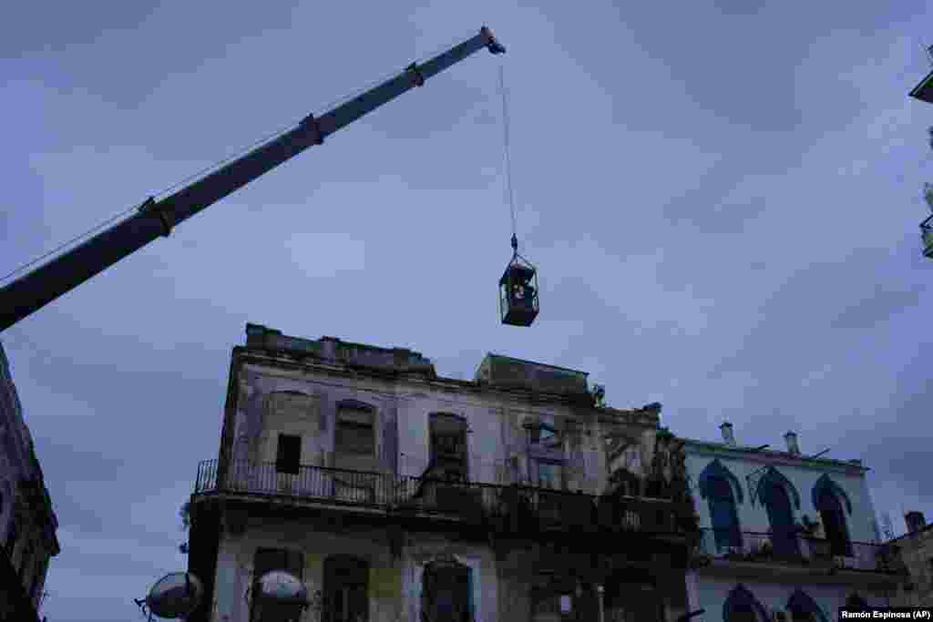 Una grúa levanta a bomberos en una jaula hacia un edificio para buscar sobrevivientes tras el derrumbe parcial de un edificio en La Habana, Cuba, el 4 de octubre de 2023. (AP Foto/Ramón Espinosa)