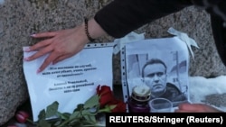 Una mujer coloca un cartel con una cita del líder de la oposición rusa Alexei Navalny en el monumento a las víctimas de la represión política, en San Petersburgo, Rusia, el 16 de febrero de 2024. (REUTERS/Stringer).