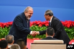 Marrero saluda al primer ministro chino, Li Qiang, en la ceremonia de apertura de la feria comercial CIIE, en Shanghai. (Hector RETAMAL/AFP)