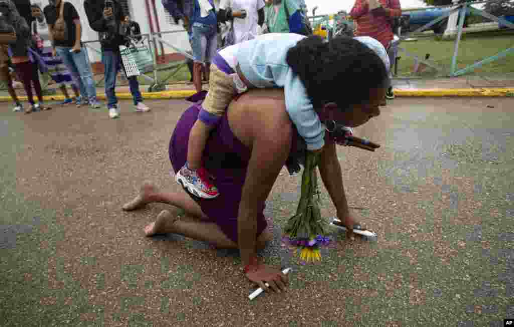 Una madre llega a su pequeño hijo a cuestas mientras camina de rodillas en peregrinación al Rincón de San Lázaro, en La Habana.