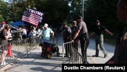 Agentes del orden mantienen guardia mientras partidarios del expresidente Donald Trump se reúnen en la entrada de la cárcel del condado de Fulton, donde se espera que Trump se entregue. (REUTERS/Dustin Chambers)