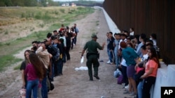 Foto de archivo. Migrantes junto al muro fronterizo mientras un agente de la Patrulla Fronteriza realiza un recuento en Eagle Pass, Texas, el 21 de mayo de 2022. (Foto AP/Dario Lopez-Mills, Archivo)