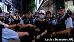 La policía detiene a una mujer en el Parque Victoria, en Hong Kong, en el aniversario 34 de la masacre de Tiananmén. (AP/Louise Delmotte).