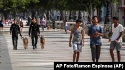 La gente camina en el Paseo del Prado mientras miembros de la policía patrullan en La Habana, Cuba, el lunes 11 de julio de 2022. 