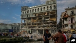 Personas observando los trabajos de rescate luego de una explosión letal que dañó el hotel Saratoga, en La Habana, el viernes 6 de mayo de 2022. (AP Foto/Ramón Espinosa)