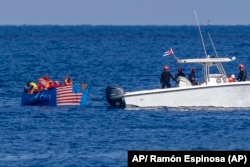 Personas a bordo de una balsa con una bandera estadounidense pintada a un costado son detenidas por la Guardia Costera de Cuba, el 12 de diciembre de 2022.