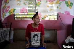 Carmen Llanes posa para una foto con una foto de su hijo Yonimiler Llanes, quien desapareció en un barco migrante casero en algún lugar entre Cuba y el sur de Florida, en Finca Favorito, Cuba, el 19 de junio de 2024. REUTERS/Alexandre Meneghini