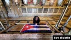 El sacerdote Kenny Fernández Delgado ora frente a una bandera cubana. (Foto: Facebook)