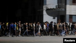 Agentes de civil con palos marchan y gritan consignas progubernamentales después de una protesta durante un apagón el 30 de septiembre de 2022. 