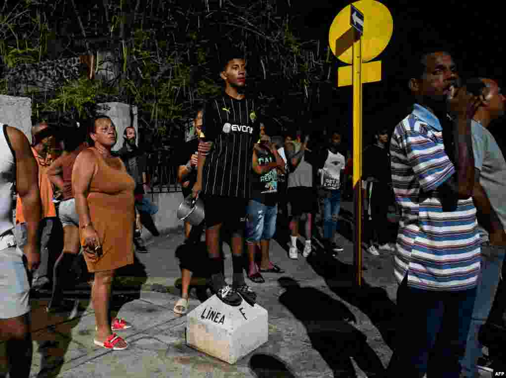 Vecinos observan desde la acera el enfrentamiento entre los seguidores del gobierno y los manifestantes, en El Vedado, La Habana. (YAMIL LAGE / AFP)