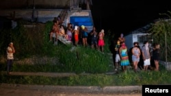 Cubanos durante un apagón, algunos se cubren el rostro para participar en protestas.