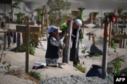 Mujeres uigures decoran una tumba en las afueras de Hotan, en la región de Xinjiang (Foto: AFP).