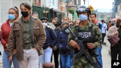 Un soldado pasa junto a los votantes que hacen fila en un colegio electoral durante la segunda vuelta de las elecciones presidenciales en Bogotá, Colombia. (Foto: AP/Jaime Saldarriaga)