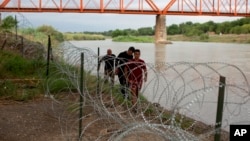 Tres cubanos llegan a suelo estadounidense tras cruzar el Río bravo en Eagle Pass, Texas, el 22 de mayo de 2022. Al otro lado de la frontera muchos cubanos temen que un cambio migratorio les impida llegar a Estados Unidos. (AP Foto/Dario Lopez-Mills)