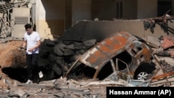 Un hombre camina sobre escombros en el lugar donde se produjo un ataque aéreo israelí, en un suburbio de Beirut, el 29 de septiembre de 2024. (AP Foto/Hassan Ammar)