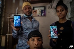 Emilio Román (izq. arriba), junto a sus familiares muestra fotos de sus hijos detenidos. AP Photo/Ramon Espinosa