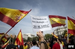 Un hombre muestra una consigna, entre banderas españolas, durante la manifestación esta mañana en la madrileña plaza de Cibeles en contra del referéndum independentista.