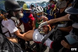 Un grupo de personas socorre a un manifestante herido tras enfrentarse a la policía durante una marcha antigubernamental en Caracas.