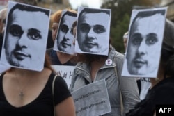 Manifestantes frente a la embajada rusa en Praga portan máscaras con el rostro del cineasta ucraniano Oleg Sentsov.