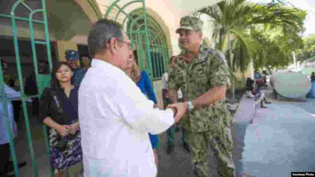 El capitán Sam Hancock, comandante de la misión Promesa Continua 2015, presenta una moneda de la misión al embajador de Cuba en Haití, Ricardo García Nápoles, en el hospital Renaissance.