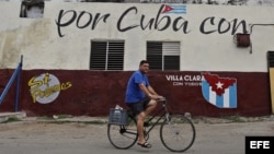 Un hombre cruza en bicicleta frente a un muro con mensajes alusivos a las elecciones generales en Cuba.