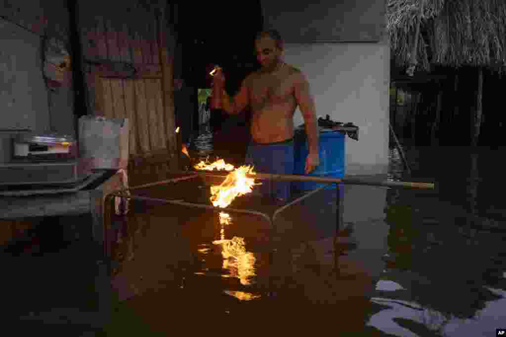 Un hombre enciende carbón para cocinar la cena en su casa inundada después del paso del huracán Helene en Guanimar, provincia de Artemisa, Cuba, el miércoles 25 de septiembre de 2024. (Foto AP/Ramon Espinosa)