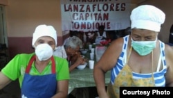 Dos mujeres del proyecto "Capitán Tondique" sirven alimentos en un almuerzo a desamparados en Matanzas.