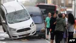 Los residentes conversan junto a automóviles amontonados luego de las inundaciones en el barrio De La Torre de Valencia, este de España, el 30 de octubre de 2024.