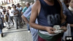 Un hombre cuenta dólares frente a una Casa de Cambio.