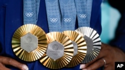 Simone Biles, de Estados Unidos, levanta sus medallas después de la final individual por aparatos de gimnasia artística femenina en los Juegos Olímpicos de Verano de 2024. (Foto AP/Charlie Riedel, Archivo)