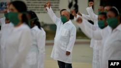 Médicos cubanos alzan sus puños en ceremonia de despedida antes de su partida a Andorra, en marzo pasado. (Yamil Lage/AFP)