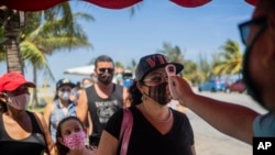 Varias personas hacen fila para que les tomen la temperatura con el fin de saber si están infectadas con el coronavirus, en un retén de la policía en La Habana. (AP Foto/Ramón Espinosa)