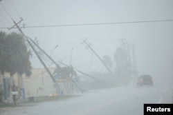 Un automovilista pasa junto a postes de electricidad rotos por fuertes ráfagas de viento mientras el huracán Milton se acerca a Fort Myers, Florida, EE. UU., el 9 de octubre de 2024. REUTERS/Ricardo Arduengo