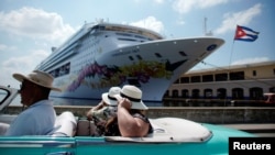 Turistas pasean en un convertible cerca de la terminal de cruceros.