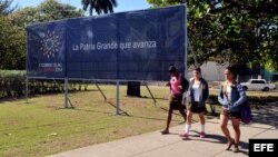 Jóvenes caminan frente a un cartel de la II Cumbre de la Celac.