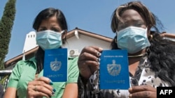 Inmigrantes cubanas muestran sus pasaportes mientras protestan frente a la agencia de la ONU para refugiados en Costa Rica en abril de 2020. Ezequiel BECERRA / AFP