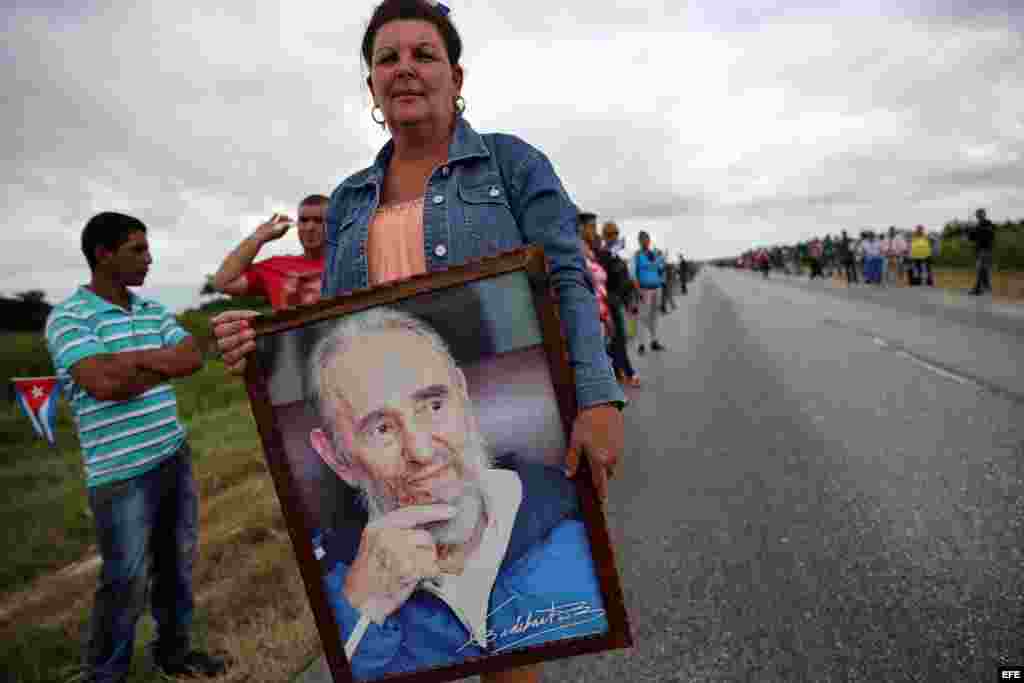 Una mujer, que espera junto a miles de personas el paso de la caravana con las cenizas del fallecido líder cubano Fidel Castro, sostiene un cuadro con una fotografía de Fidel Castro hoy, 1 de diciembre de 2016, en las afueras del pueblo de Jatibonico, en 