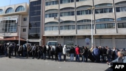 Los sirios esperan en fila afuera de un edificio oficial para resolver su situación con las nuevas autoridades del país, en Tartus, en el oeste de Siria, el 17 de diciembre de 2024.