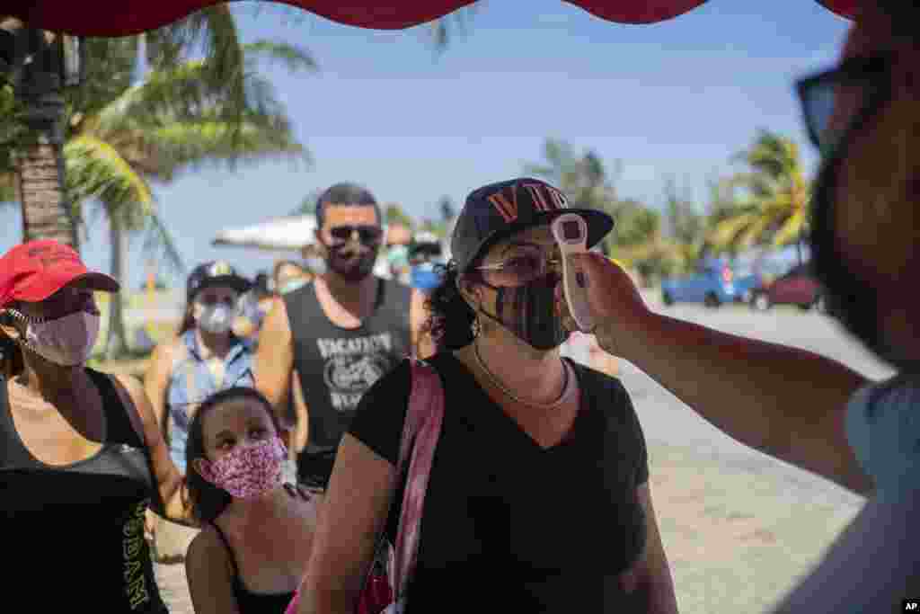 Varias personas hacen fila el lunes 10 de agosto de 2020 para que les tomen la temperatura con el fin de saber si están infectadas con el coronavirus, en un retén de la policía en la provincia de La Habana, Cuba. (AP Foto/Ramón Espinosa)