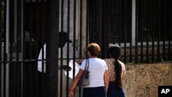 Dos personas esperan su turno en el exterior de la embajada de Estados Unidos el día después de la reapertura de los servicios consulares, en La Habana. (Ramón Espinosa/AP)