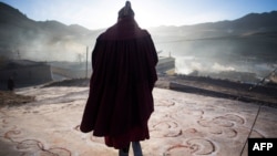 Monje budista tibetano contempla la salida del sol durante celebración de Año Nuevo Tibetano.