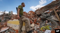 Un soldado ucraniano mira los escombros de una escuela destruida hace unos días durante un ataque con misiles en las afueras de Járkiv, Ucrania, el 5 de julio de 2022. (AP Foto/Andrii Marienko).