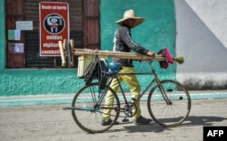 Un hombre camina con su bicicleta de la mano por una calle de Santa Clara.