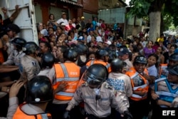 Miembros de la Policía Nacional Bolivariana contienen a un grupo de personas que trata de ingresar a un supermercado donde se venden dos kilos de pasta por persona.